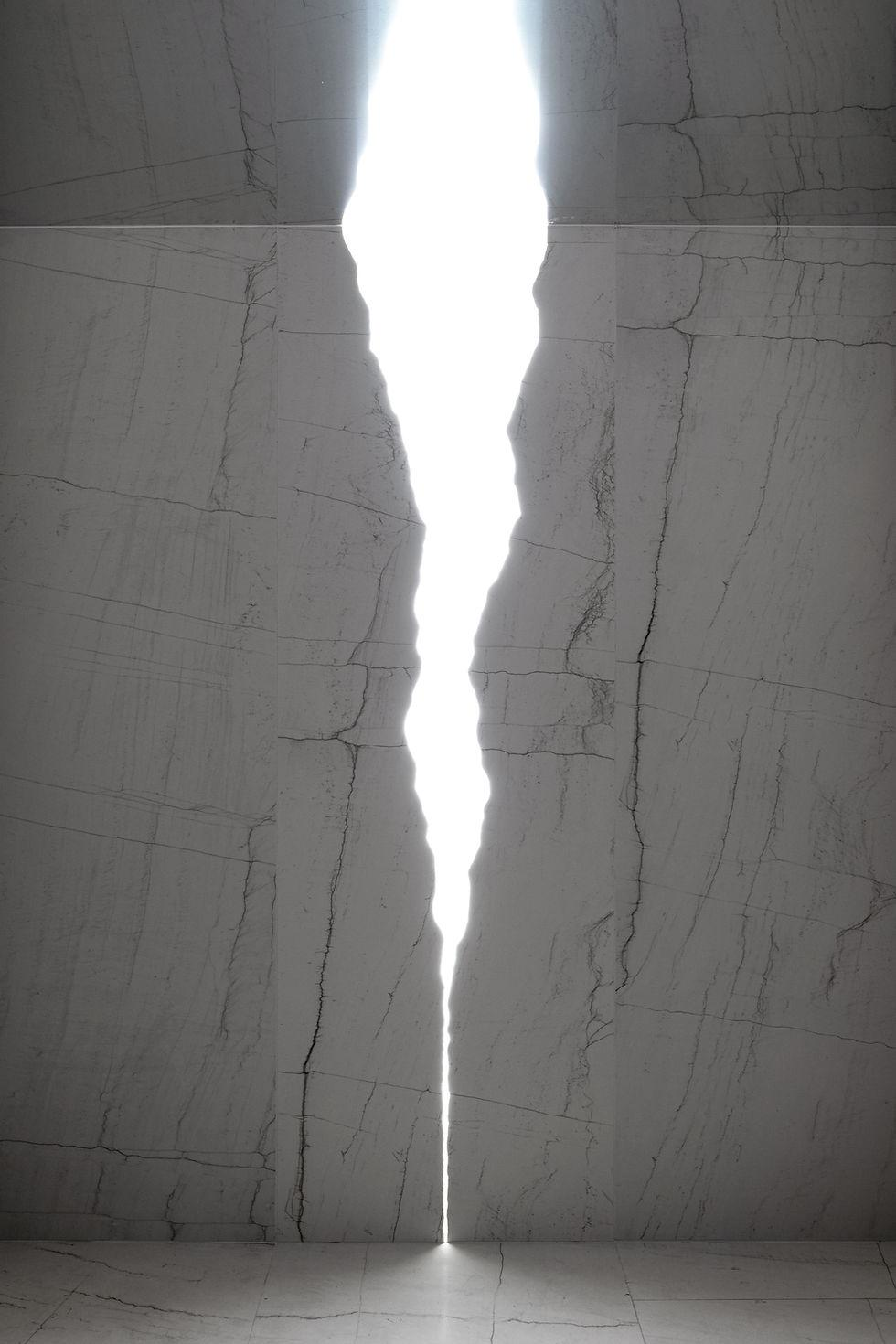 Una grieta de luz atraviesa dos paredes de piedra.